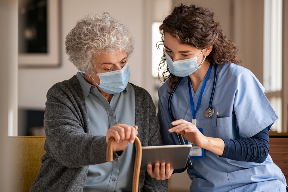 A senior and a caregiver looking at a tablet