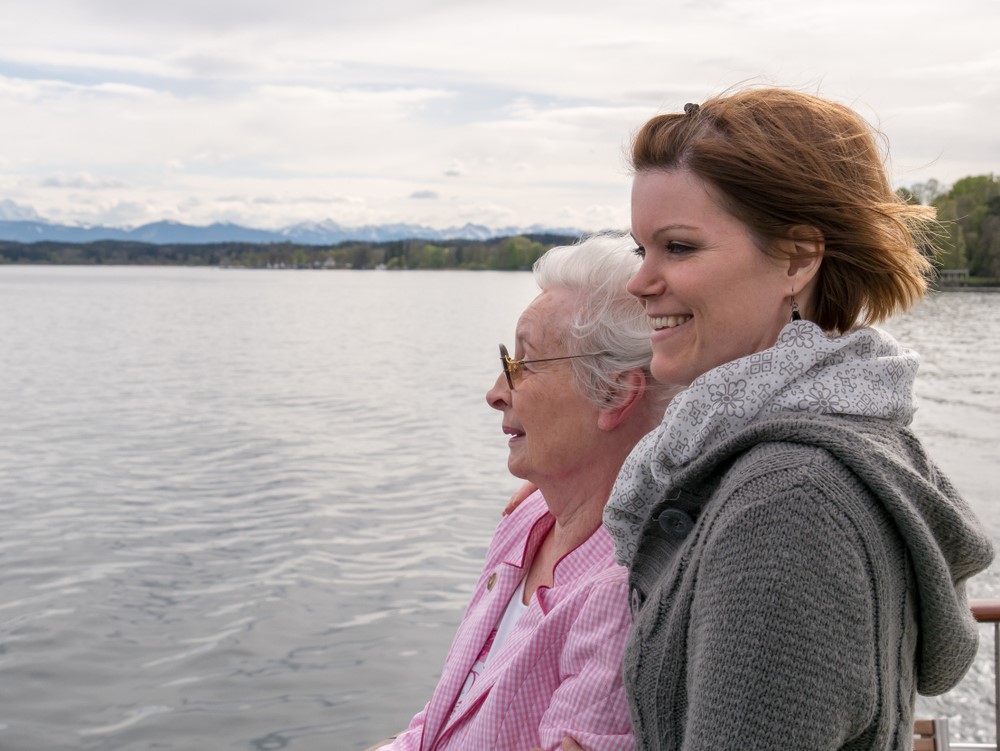 A senior and a daughter or grandaughter on a beach after they've been traveling