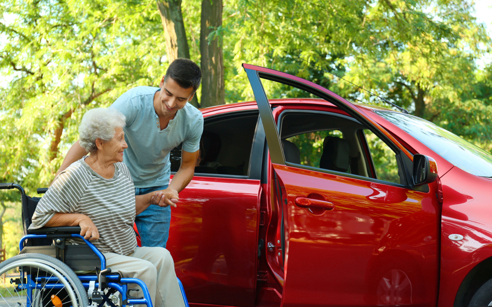 A young man helping a senior with her wheelchair to make traveling easier