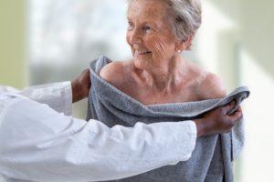 A senior woman being handed a towel by a caregiver