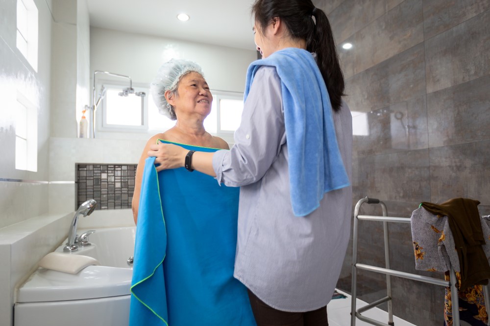 An Asian daughter helping her mother to bathe