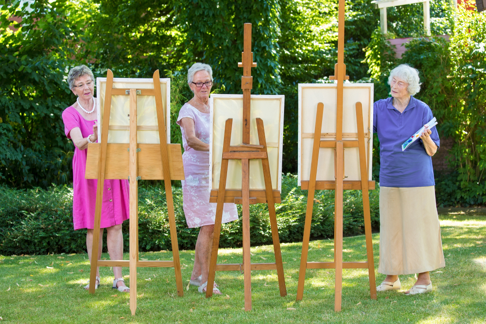 A group of older women painting outdoors