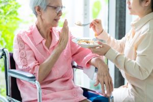 An elderly Asian woman refusing to eat