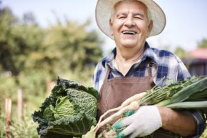 A senior man holding raw dark leafy greens, as a reference to how greens can help with cognition in seniors