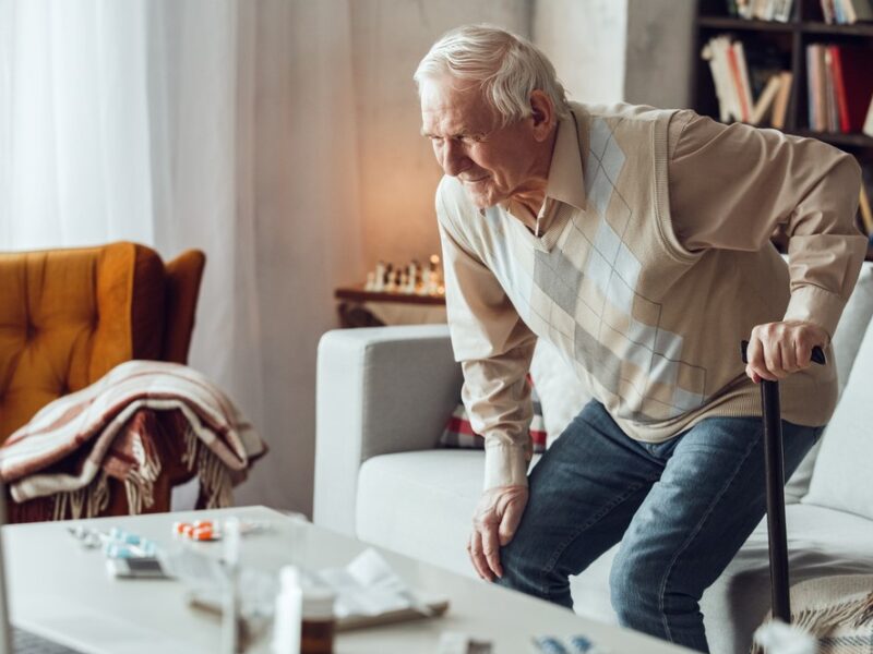 A senior man struggling to stand up after sitting