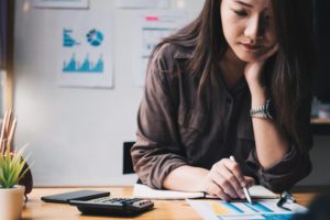 A young woman using a calculator to look at caregiving and finances