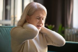 A senior woman experiencing pain in the back of her neck - showing muscle pain in seniors