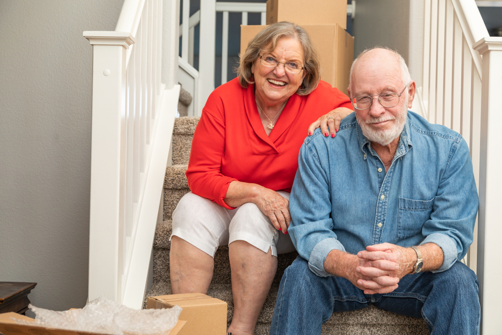 A senior couple surrounded by moving boxes based on the idea of moving a senior in with you