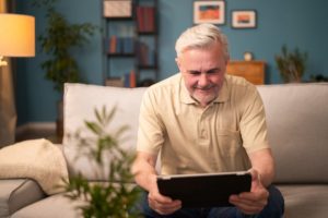 An elderly man playing games on a tablet, highlighting the idea of tablet apps for seniors