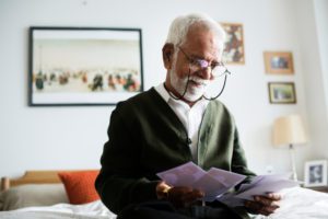 An Indian or Pakistani man at home with glasses reading, focusing on the concept of caregiving and culture