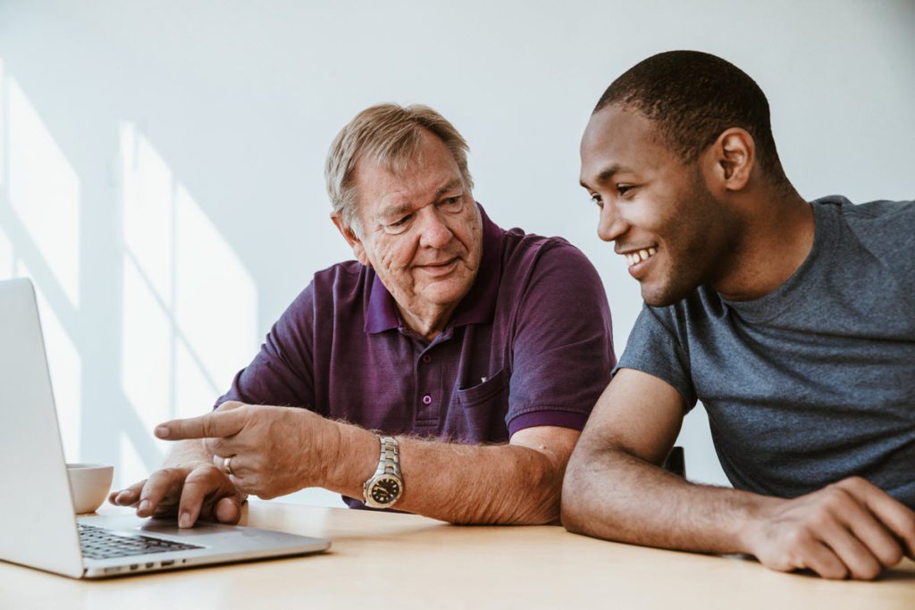 Young man teaching a senior to use technology