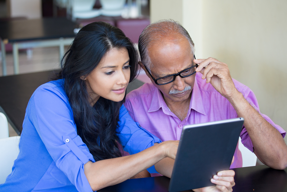 A young woman teaching a senior to use technology