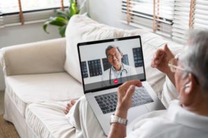 An Asian senior lying on the couch talking on a video call, highlighting the idea of isolation in older adults