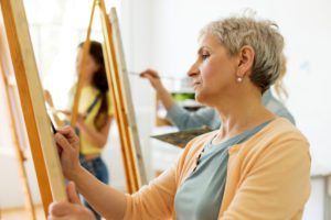 A senior woman at art school to access the benefits of art therapy for the elderly