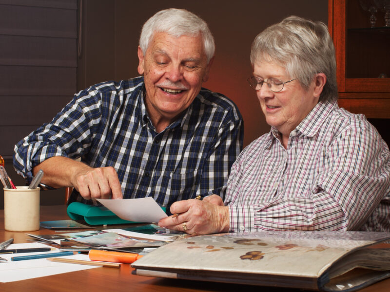 A retired couple using a scrapbook as one of their holiday activities for seniors