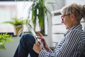 A senior woman sitting down and using one of the best tablets for seniors