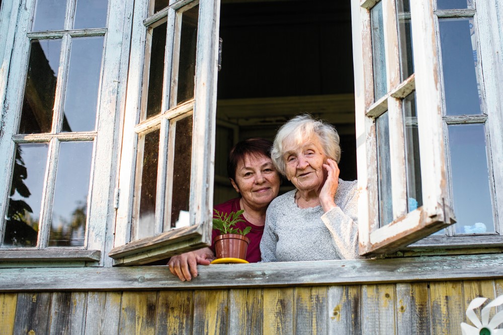 A daughter and mother looking out of an apartment window