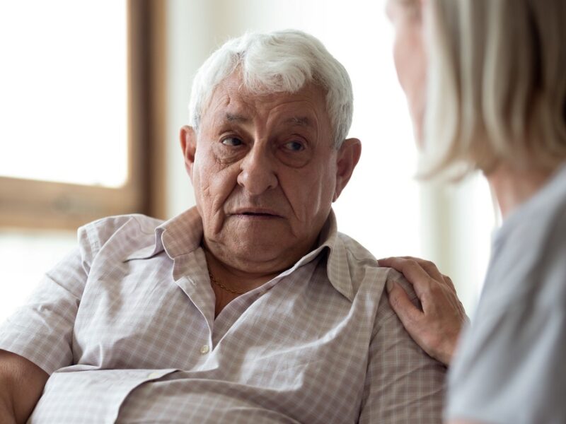 A middle aged woman comforting her aging father, focusing on the idea of talking to seniors