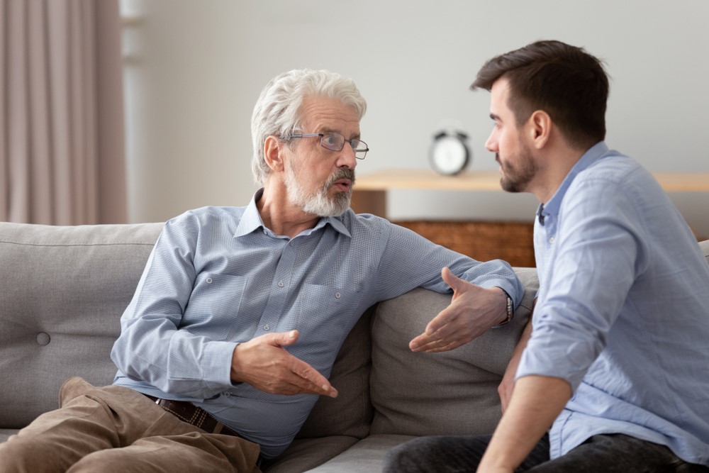 A young man and his senior father engaged in a difficult conversation