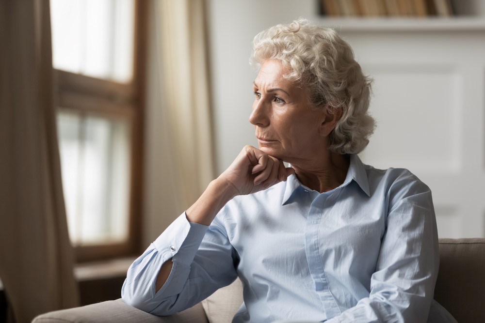 A senior woman sitting upset at home, focusing on the idea of safety for seniors who live alone