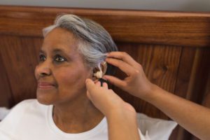 An African American woman being fitted for an hearing aid, highlighting the benefits of ordering hearing aids online