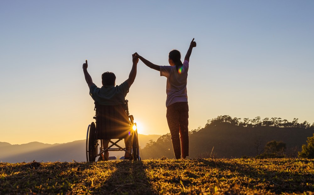 A man in a wheelchair holding up his hands next to a woman, focusing on the idea of disability awareness