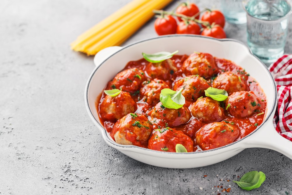 A white dish of baked meatballs