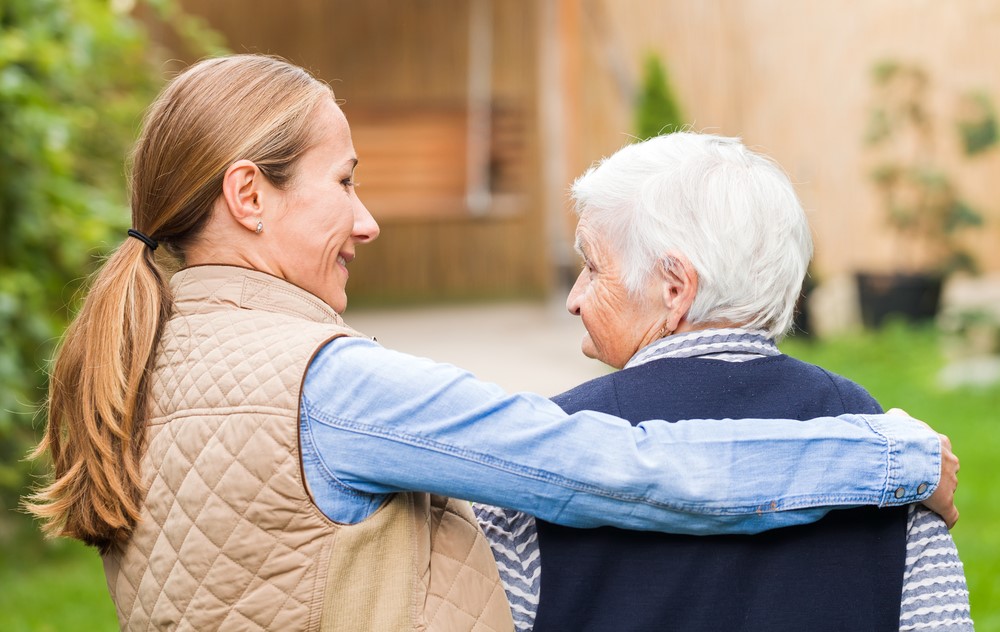 A caregiver with her arms around a senior