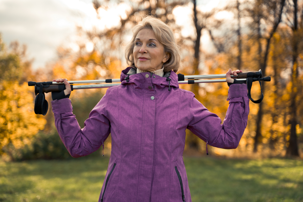 A senior woman holding walking poles in the park