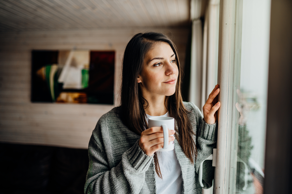 A young woman looking out the window, highlighting the idea of self care