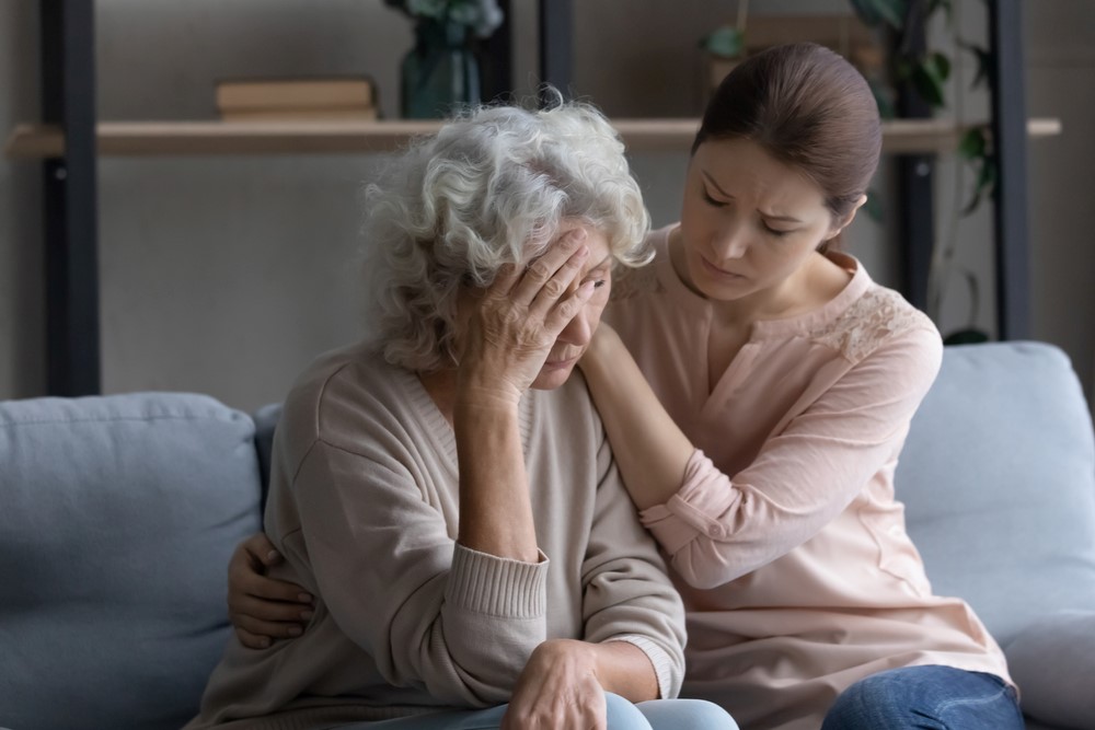 A woman comforting her sad aging mother