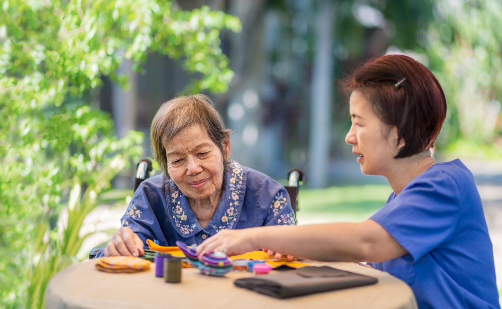 A Korean senior working on a puzzle with her daughter or a caregiver