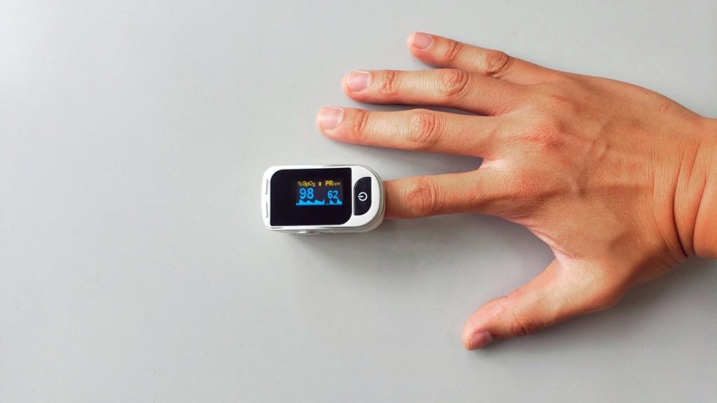 A digital fingertip oximeter on someones hand