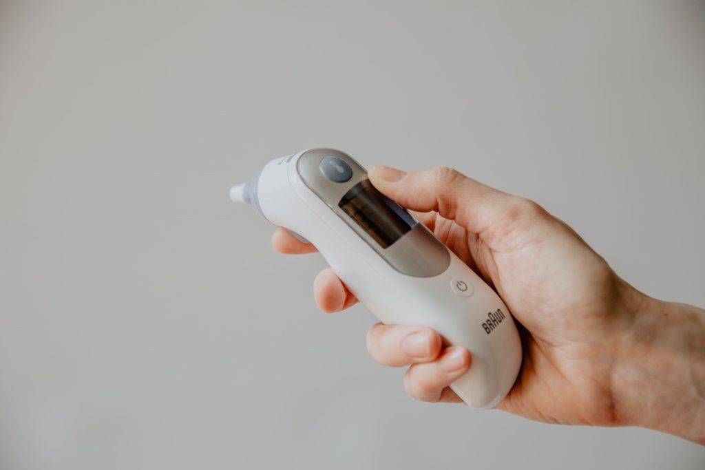 A hand holding a forehead thermometer