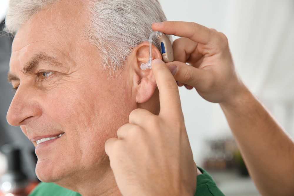 A senior man being fitted with a hearing aid