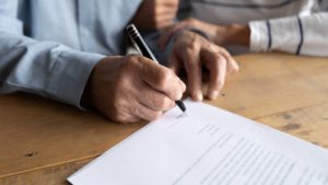 A senior signing the paperwork for a financial trust document