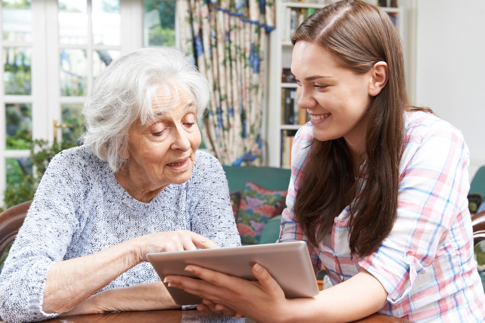 A granddaughter teaching her senior mother how to use a tablet