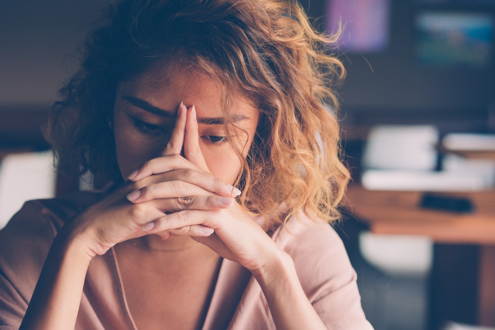 A young woman resting her face against her hands due to caregiver burnout