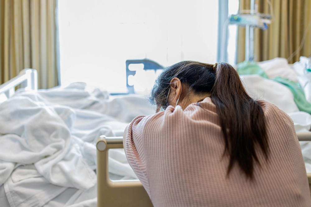 An exhausted young woman next to a hospital bed