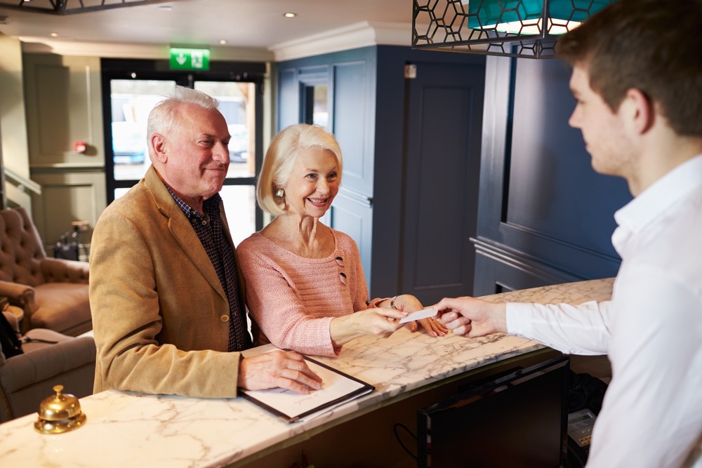 A senior couple checking into a hotel highlighting the idea of dementia friendly hotels