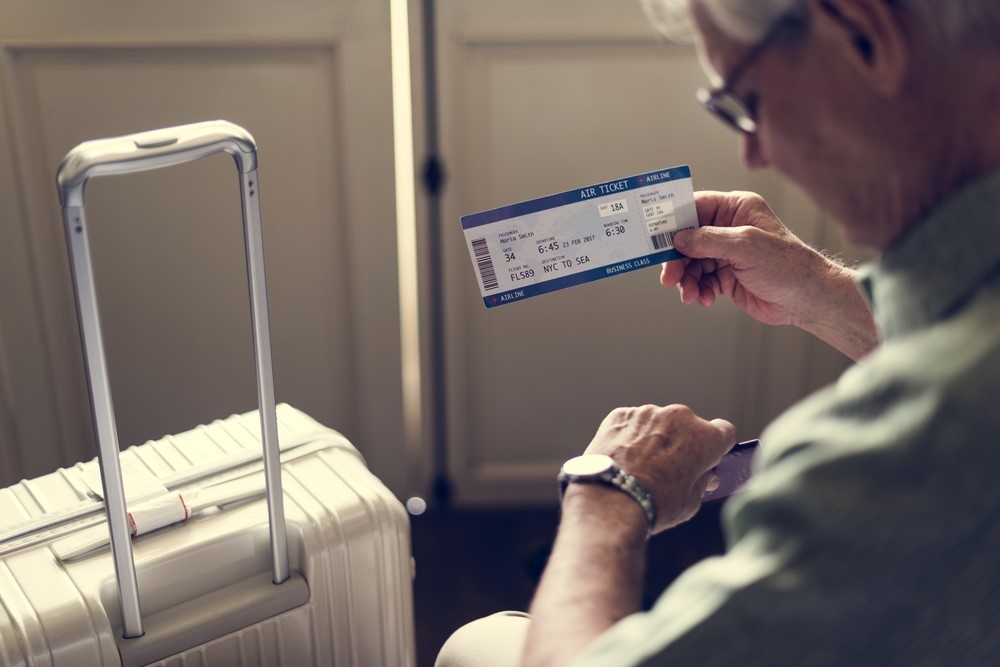 A senior man looking at his watch with a ticket in his hand