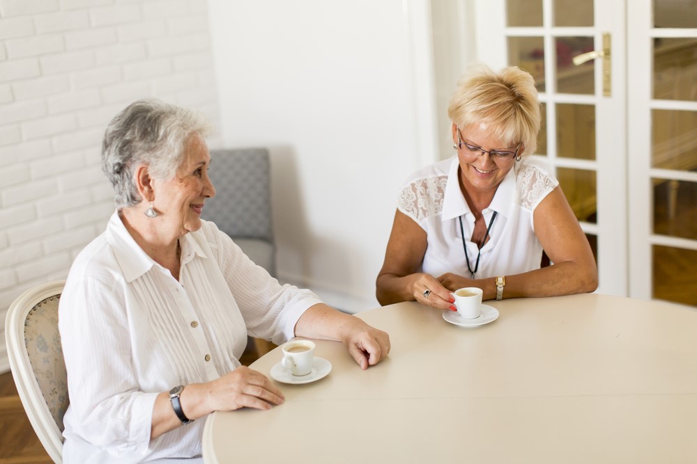 A senior woman and her daughter at home drinking coffee