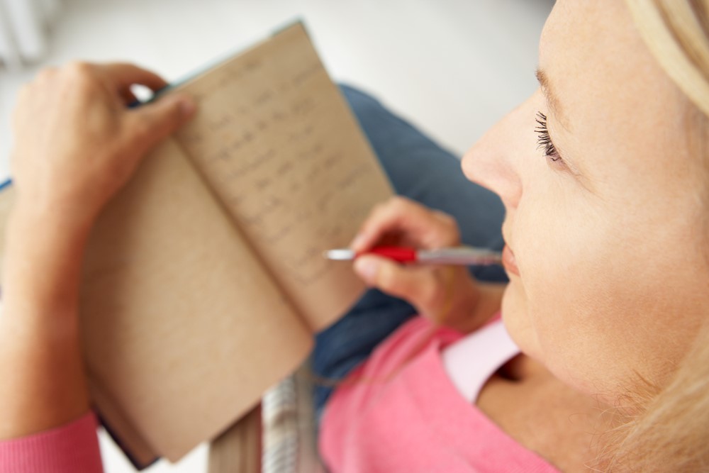 A senior woman writing in a book, as an illustration of how journaling for seniors can be powerful