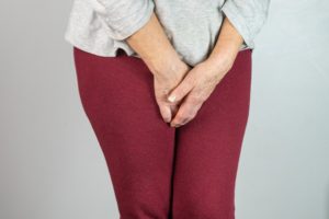 A senior woman with her hands over her crotch, showing the idea of elderly incontinence products