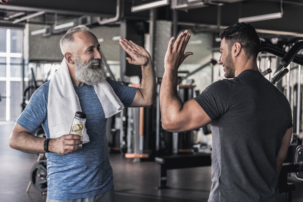 Two men high fiving each other at a gym