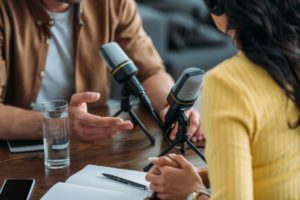 Two people sitting at a table recording a podcast or a radio broadcast