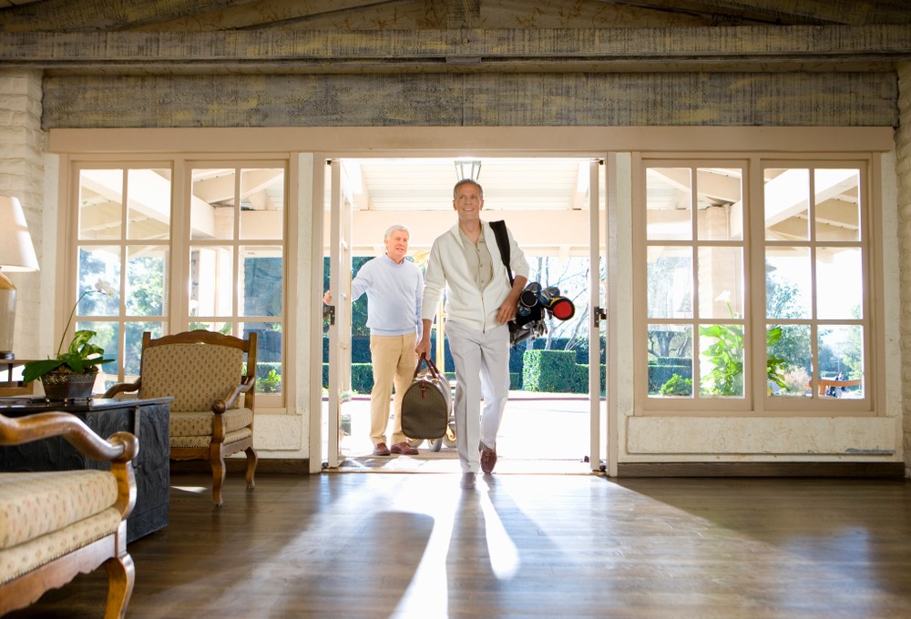 Two senior men entering a hotel or a large house