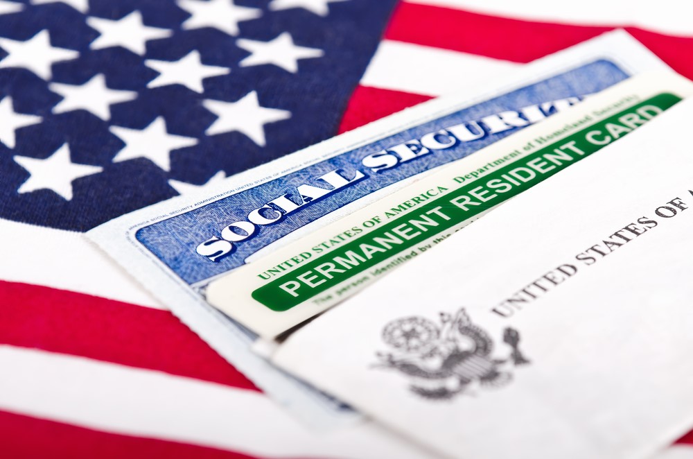 A Social Security card, a green card, and an American flag, highlighting the idea of a visa and retirement