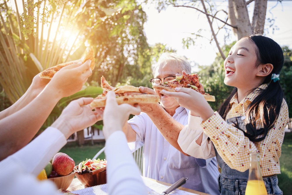 A Vietnamese family sharing pizza outdoors