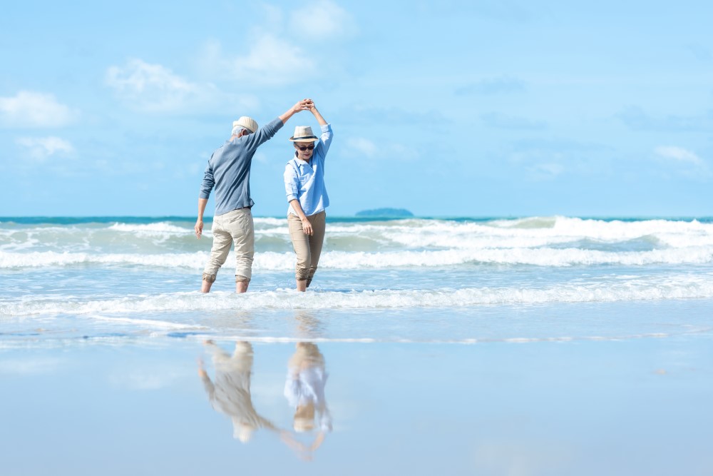 A senior couple dancing in the waves, celebrating their retirement